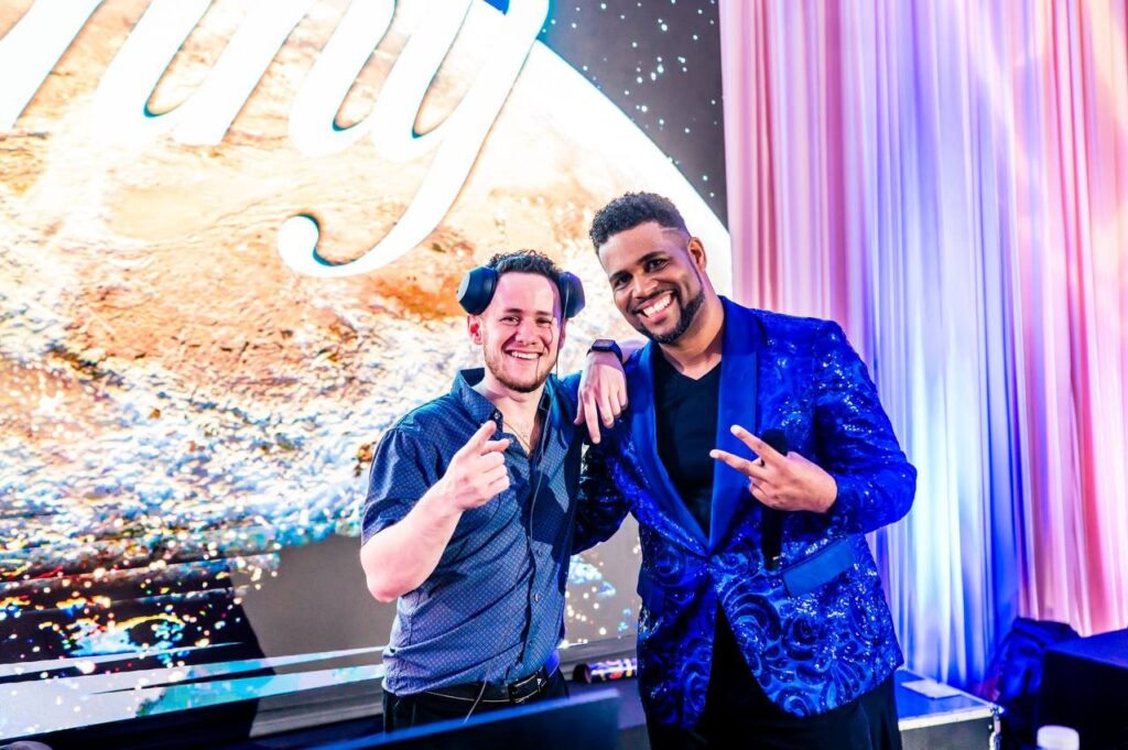 Two event entertainers smiling together beside the DJ booth and LED video wall