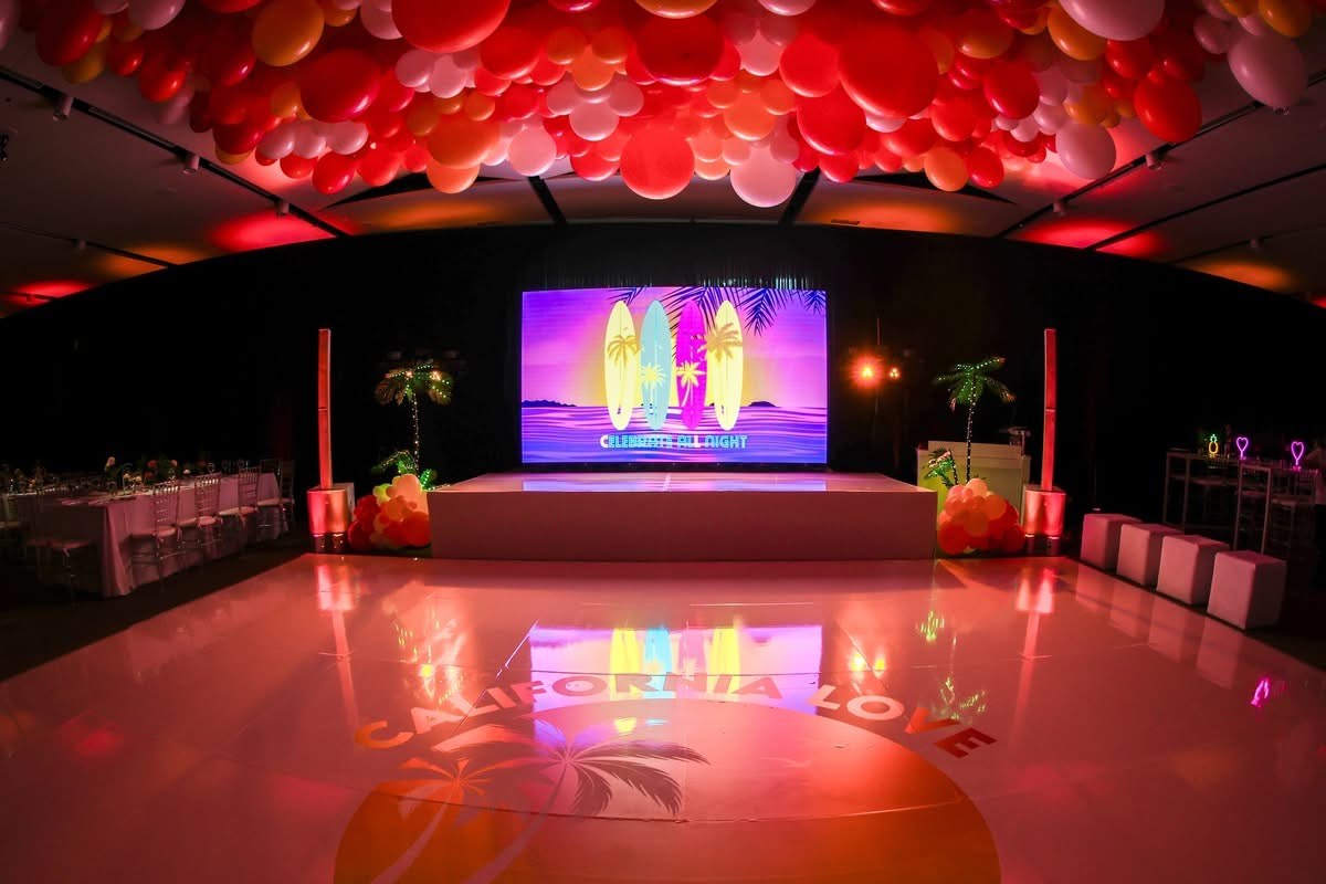 Event room with a colorful LED wall, dance floor and ceiling balloons
