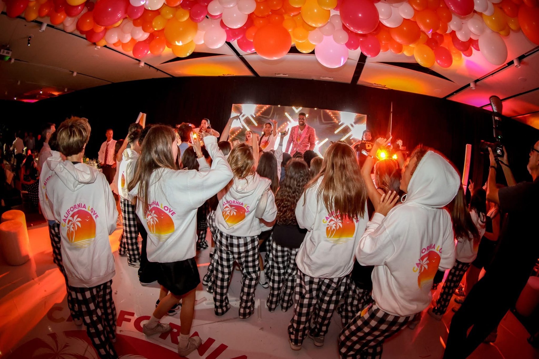 Party guests dancing beneath colorful balloons